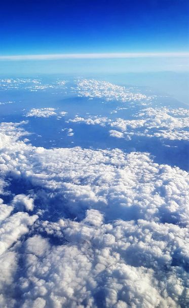 A beautiful scenery of the earth and white fluffy clouds seen from a plane - Fotoğraf, Görsel