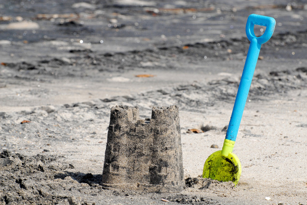 Sand castle and a plastic shovel at a beach - Фото, изображение