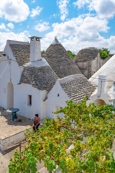 Csoportja gyönyörű Trulli, hagyományos apuliai száraz kő kunyhó régi házak kúpos tető Itria Valley, Puglia, Olaszország, grapefruit fa és paraszt, függőleges - Fotó, kép