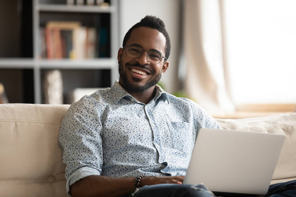 Head shot portrait smiling African American man relaxing with laptop - Foto, immagini