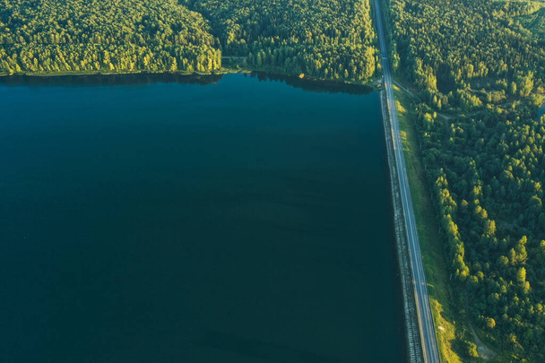 View from the drone. View from above on the dam. Road on the dam. Road. Green forest. Summer. Evening. Green. - Photo, Image