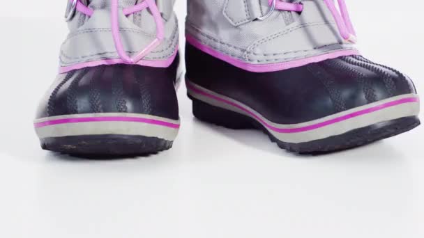 Malá dívka růžové a šedé teplé a vodotěsné zimní boty na bílém pozadí. - Záběry, video
