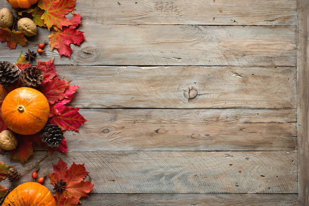 Autumn composition - Pumpkins, autumn maple leaves, pine cones  on wooden background, creative flat lay, top view, copy space. Seasonal autumn holiday concept. - Photo, image
