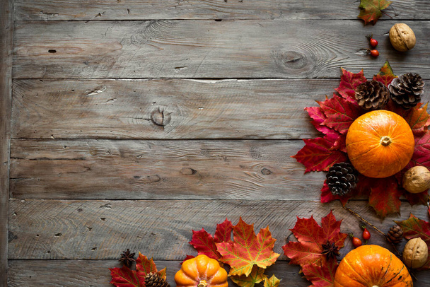 Herfst compositie - Pompoenen, herfst esdoorn bladeren, dennenappels op houten achtergrond, creatieve platte lay, bovenaanzicht, kopieerruimte. Seizoensgebonden herfstvakantie. - Foto, afbeelding