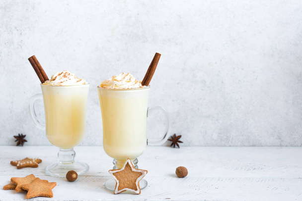 Christmas Eggnog drink with festive decor, gingerbread cookies and winter spices on white, copy space. Homemade eggnog for Christmas and winter holidays. - Foto, Imagen