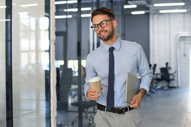 Businessman walking in office corridor with takeaway coffee - Photo, image