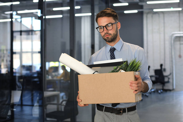 Sad dismissed worker is taking his office supplies with him from office - Photo, Image