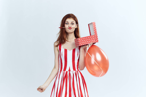 Cheerful woman with red balloons gift striped dress light background fun holiday - Foto, imagen