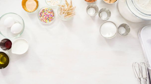 Flat lay. Step by step. Ingredients on the white table to make unicorn chocolate cupcakes. - Photo, Image