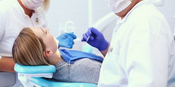Ritratto di un dentista che cura i denti di una giovane paziente - Foto, immagini