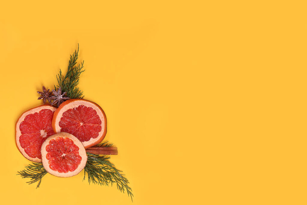 Composizione creativa natalizia posa piatta di arance secche, rami di abete, anice e cannella su uno sfondo giallo brillante. - Foto, immagini