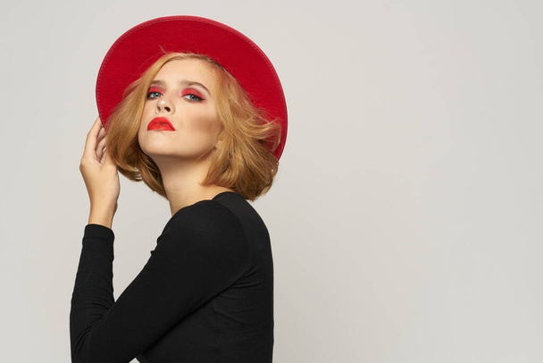 Μοντέρνα γυναίκα σε κόκκινο καπέλο μαύρη μπλούζα κόκκινα χείλη περικοπεί προβολή φως συναισθήματα φόντο - Φωτογραφία, εικόνα