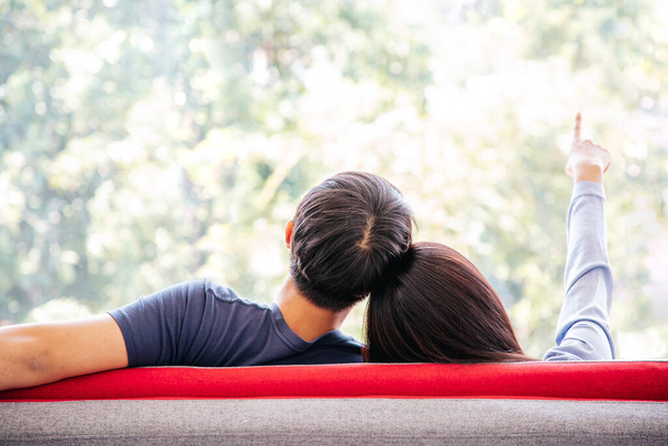 Vista posteriore di Bella coppia seduta sensazione di relax e confortevole sul divano rosso con Green Outdoor Park View. Vacanze. SPAZIO DI COPIA. - Foto, immagini