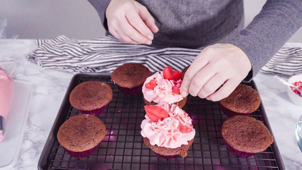 Stap voor stap. Decoratie van rode fluwelen cupcakes met chocolade rode harten en kussen. - Foto, afbeelding
