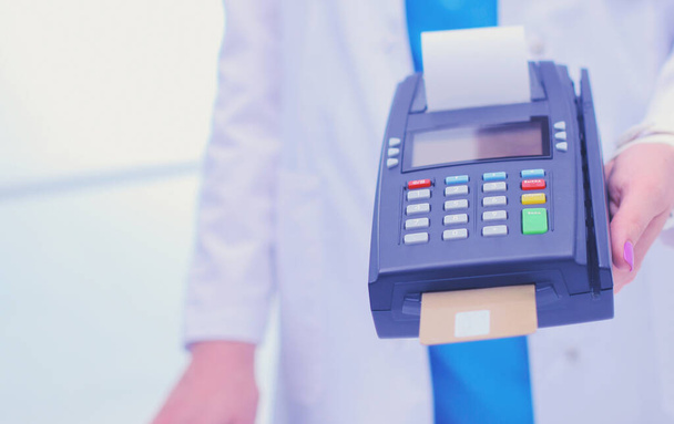 Doctor is holding payment terminal in hands. Paying for health care. Doctor - Foto, afbeelding
