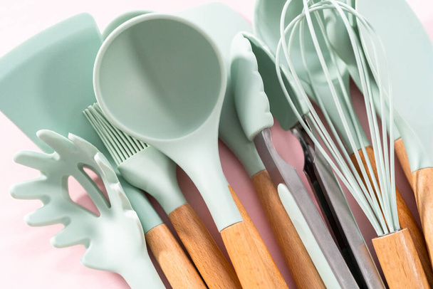 Новий синій силіконовий кухонний посуд з дерев'яними ручками на рожевому фоні
. - Фото, зображення
