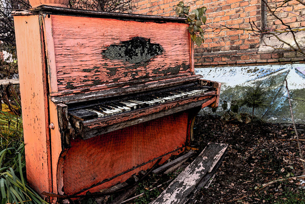 Stare złamane czerwone pianino z obraną farbą od deszczu i wiatru, na zewnątrz w jesienny dzień. Odrzucony niepotrzebny instrument muzyczny. - Zdjęcie, obraz