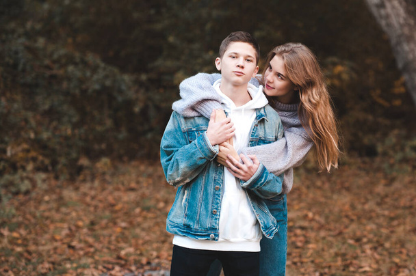14-15 yaşlarında iki genç kız ve erkek birbirlerine sarılıp sonbahar doğası boyunca dışarıda eğleniyorlar. Birliktelik.  - Fotoğraf, Görsel