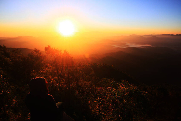 MAEHONGSON, Tajlandia-GRUDZIEŃ 11, 2015: Piękna sylwetka azjatki siedzącej samotnie i samotnie w naturalnym złotym wschodzie słońca i roztargnionej patrząc na Horyzont na górze doliny - Zdjęcie, obraz