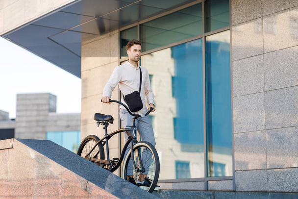 W drodze do pracy nad transportem ekologicznym. Stylowy hipster schodzący po schodach na rowerze - Zdjęcie, obraz