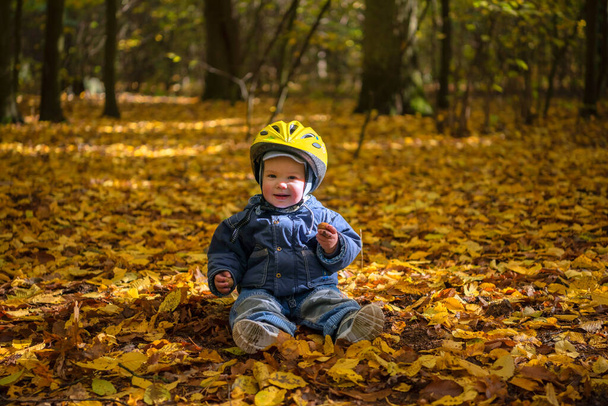 Bébé garçon souriant mignon avec casque de sécurité dans le parc d'automne - Photo, image