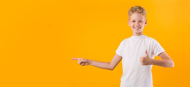Ευτυχισμένο αγόρι δείχνει τα δάχτυλα στην άκρη στο χώρο των αντιγράφων - Φωτογραφία, εικόνα