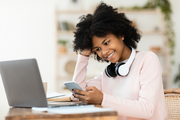 African Girl SMS-y w telefonie do pracy domowej na laptopie w pomieszczeniach - Zdjęcie, obraz