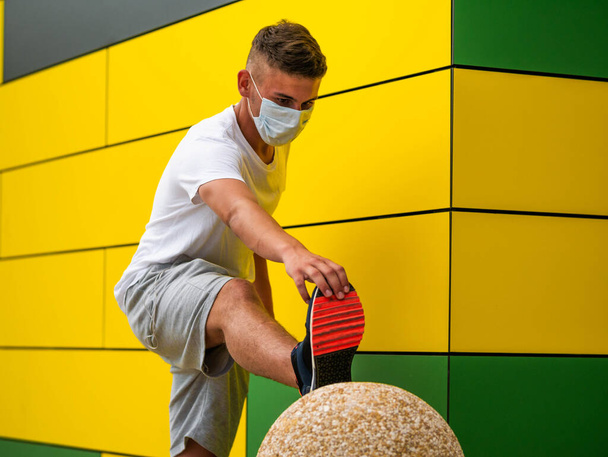 Un joven caucásico usando auriculares y ejercitándose cerca de la pared de color amarillo brillante - Foto, Imagen