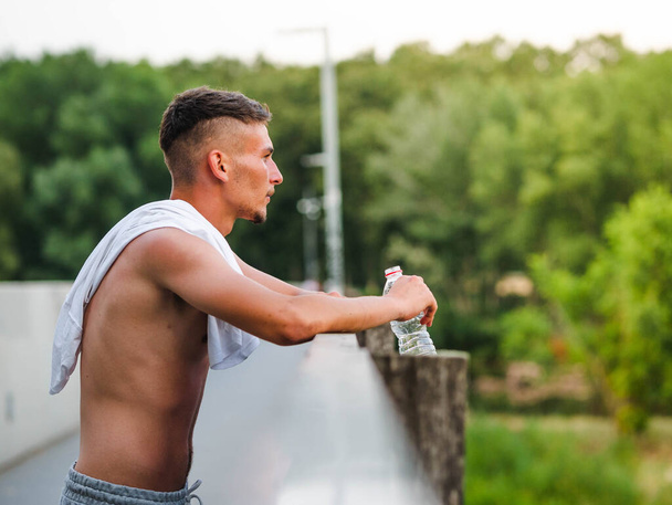 トレーニング後の若い魅力的なスポーツマン飲料水-スポーツコンセプト - 写真・画像
