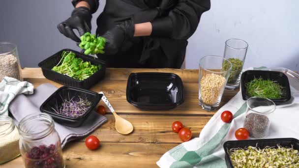 Erschießung einer Frau in schwarzer Kleidung, die Salat mit Mikrogrün und Samen kocht - Filmmaterial, Video