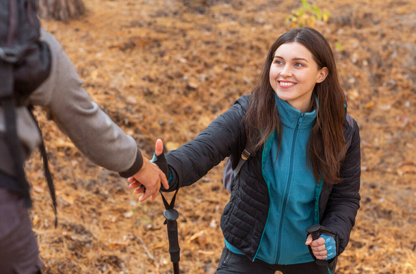 Cheerful girl taking helping hand from guy while hiking - Photo, Image