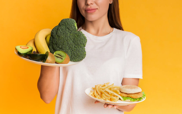Girl choosing between organic fruits and vegetables and junk food - Foto, imagen