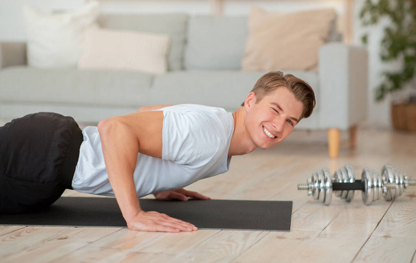 Sport and healthy lifestyle during covid. Athletic guy doing push ups looking at camera - Photo, Image