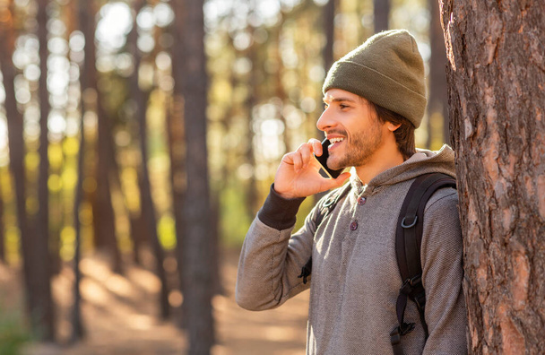 Happy young man backpacker talking on phone while hiking - Foto, afbeelding