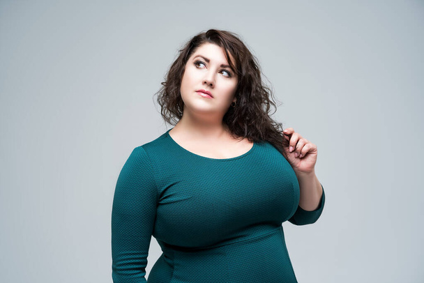 Plus size fashion model in green dress, fat woman on gray studio background, body positive concept - Fotoğraf, Görsel