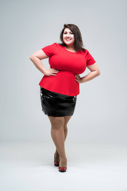 Happy plus size fashion model in red blouse and black skirt, fat woman on gray studio background, body positive concept - Fotografie, Obrázek