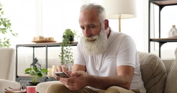 Old man beckoning someone while using mobile phone at home - Video