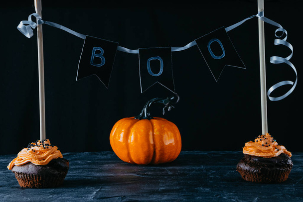  Halloween sweets, chocolate cupcakes and pumpkin on a black background. Copy space - Foto, imagen