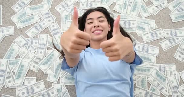 Nő feladja hüvelykujját gesztus feküdt szétszórt dollár számlák - Felvétel, videó