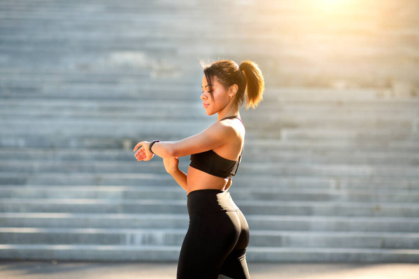 Fekete sportos nő nézi fitness karkötő edzés közben - Fotó, kép