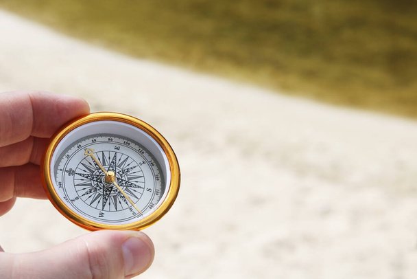 klasyczny kompas nawigacyjny latem na tle piaszczystej plaży jako symbol turystyki z kompasem, podróży z kompasem i aktywności na świeżym powietrzu z kompasem - Zdjęcie, obraz