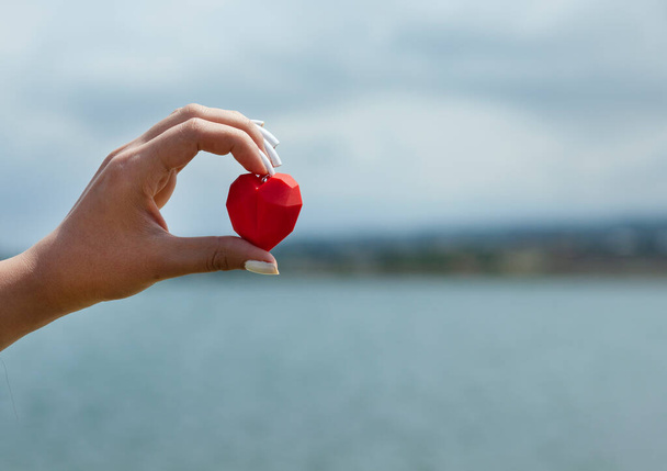 woman hand red heart in sea background - Foto, Imagen