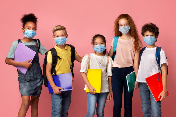 Edukacja podczas kwarantanny. Portret różnych uczniów noszących maski medyczne na różowym tle - Zdjęcie, obraz