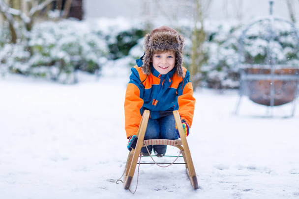Маленький мальчик, катающийся на санях зимой - Фото, изображение