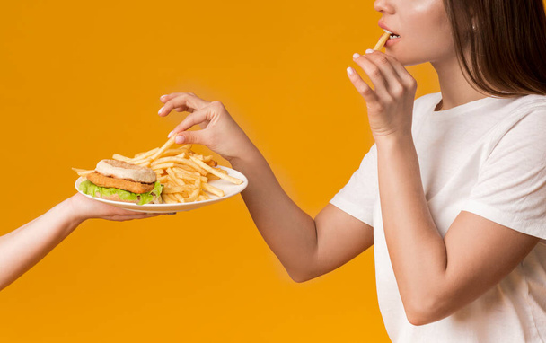 Невпізнавана жінка їсть картоплю фрі з плити швидким харчуванням - Фото, зображення