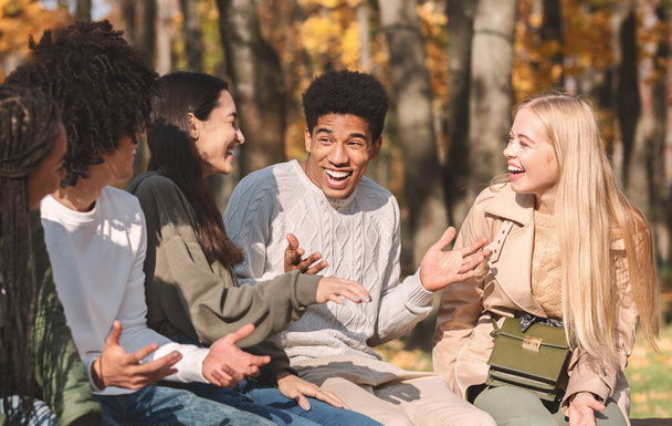 Група щасливих підлітків розмовляють і сміються в парку
 - Фото, зображення