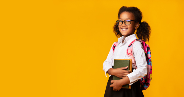 African Schoolgirl Posing With School Books Over Yellow Studio Background - Foto, afbeelding