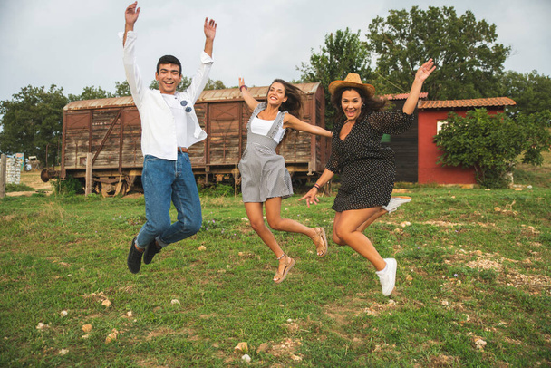 Kolme ystävää hyppää, nauraa ja pitää hauskaa tilalla. Ranch käsite valokuvaus - Valokuva, kuva