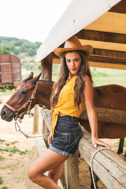 Молодая красивая женщина позирует рядом с лошадью. Ковбой Хемсворт, Ранчо Хемсворт - Фото, изображение