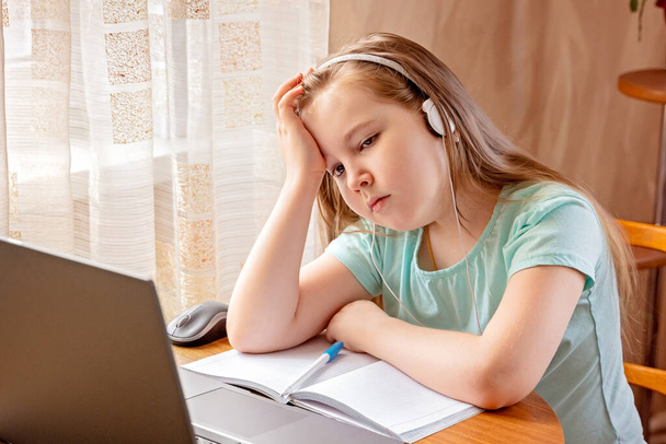 Photo of little upset pupil. Small schoolgirl browsing laptop read homework. - Foto, Bild